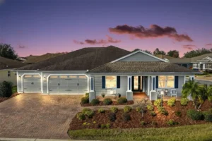 A charming single-story house with a well-maintained garden, illuminated by outdoor lights, set against a colorful sunset sky.