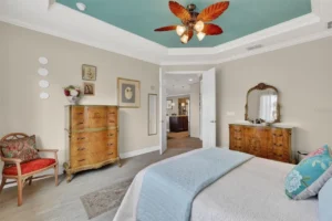 A cozy bedroom featuring a blue ceiling, wooden furniture, and light-colored walls, creating a warm and inviting atmosphere.