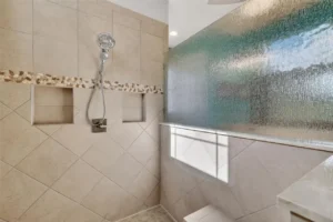 A modern shower area featuring tiled walls, a glass partition, and a sleek fixture, offering a clean and spacious look.