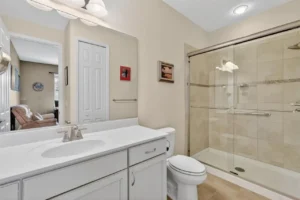 A modern bathroom featuring a glass shower, white vanity, and neutral-colored walls, creating a clean and spacious atmosphere.