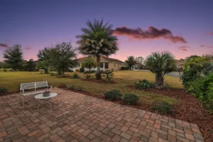A serene backyard scene at dusk with green plants, a brick patio, and a clear sky transitioning to evening shades.