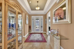 A spacious entryway featuring elegant decor, a glass display cabinet, a console table, and framed artwork, illuminated by a stylish ceiling fixture.