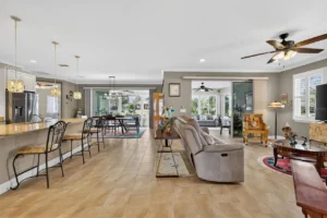 A spacious, modern living area featuring a cozy seating arrangement, dining space, and large windows allowing natural light.