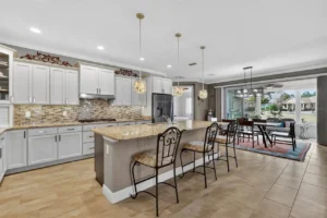 Modern kitchen featuring granite countertops, stylish cabinets, pendant lighting, and a dining area with a view of the outdoors.
