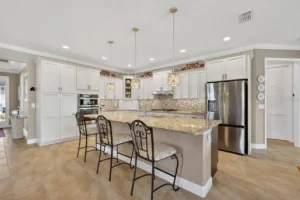 A modern kitchen featuring white cabinets, granite countertops, and stylish pendant lighting, with seating at a bar-style counter.